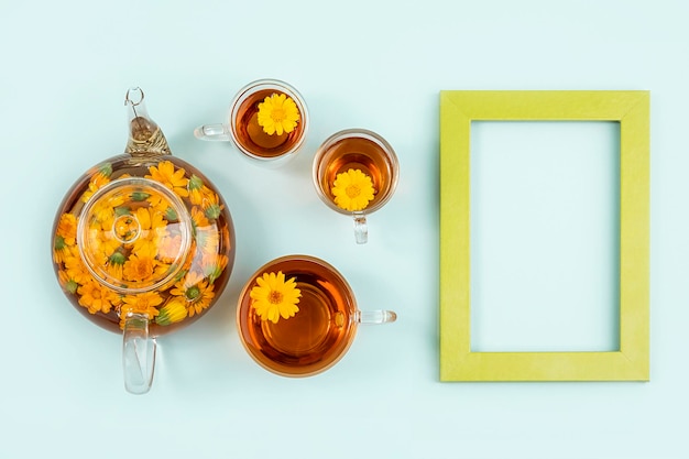 Foto chá de ervas xícaras de bule de vidro transparente de chá com flores laranja de calêndula em um fundo azul conceito de bebida calmante