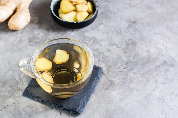 Chá de gengibre fresco em uma xícara e gengibre picado em uma tigela sobre a mesa vitaminas naturais