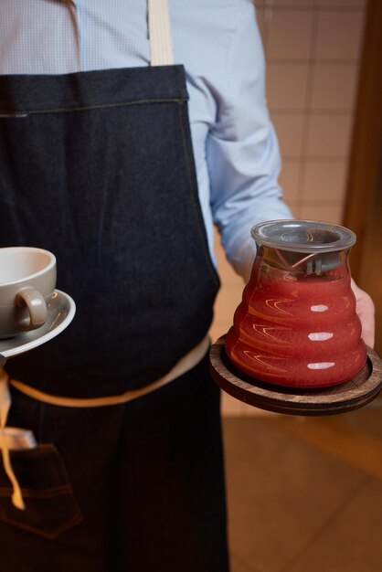 Chá de inverno em prensa francesa servido por uma garçonete Chá de inverno em prensa francesa servido com biscoito também algumas ervas ao lado e um pote de mel