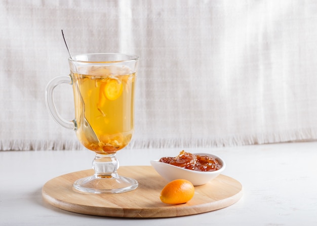 Chá de jasmim com kumquat em um copo de vidro em uma placa de madeira em branco