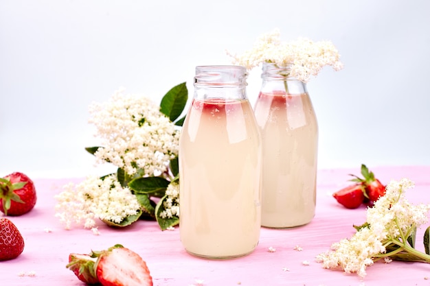 Chá de Kombucha com sabugueiro e morango em fundo rosa.