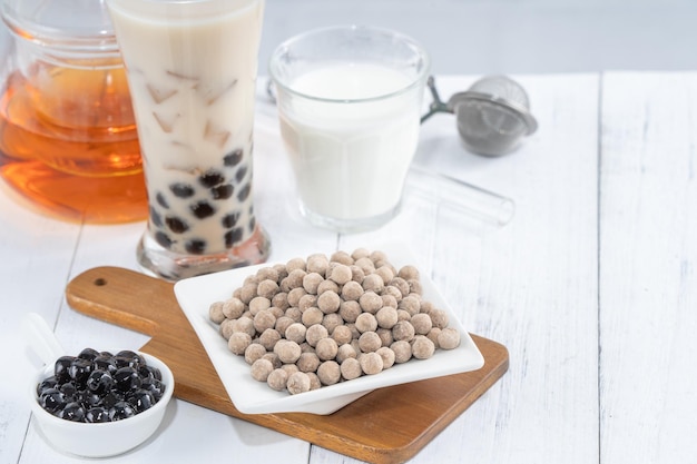 Chá de leite bolha com ingrediente de cobertura de pérola de tapioca famosa bebida taiwanesa no fundo da mesa de madeira branca em copo de bebida fechar espaço de cópia