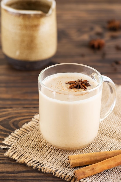 Chá de masala caseiro com leite e especiarias em uma caneca em uma mesa de madeira. Sem lactose, vegano.