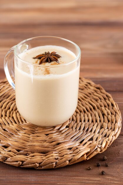 Chá de masala caseiro com raiz de gengibre de leite de coco e especiarias em uma caneca de vidro em cima da mesa