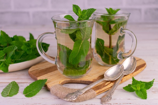 Chá de menta em copos transparentes em uma placa de madeira.