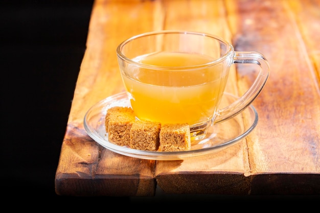 Chá de panela de cana em um copo de vidro em uma superfície de madeira royalty free
