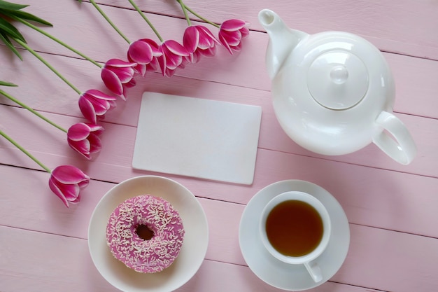 Chá de primavera.Leite plana.Prima lista de tarefas.pink tulipas flores, bule branco, caderno em branco, xícara de chá e rosquinha rosa.