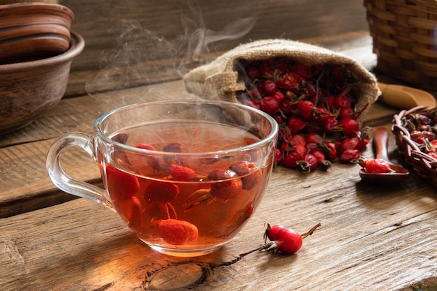 Chá de Rosa Mosqueta em fundo de madeira com frutas vermelhas