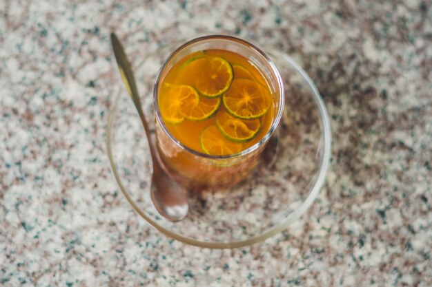 Chá de tangerina em um copo de vidro sobre uma mesa de pedra em um café