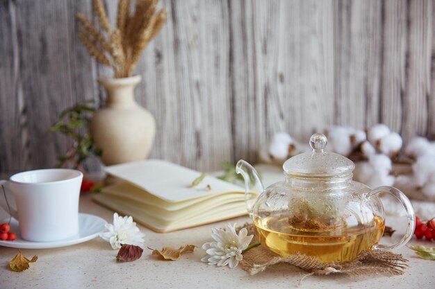 Chá de tília de ervas estéticas em bule com xícara de chá Folhas de trigo decorações de outono de algodão e caderno Atmosfera acolhedora relaxante em casa