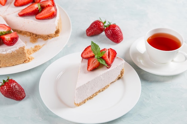 Chá doce de café da manhã e delicioso cheesecake com morangos frescos e receita caseira de menta sem assar em uma mesa de pedra azul copiar espaço