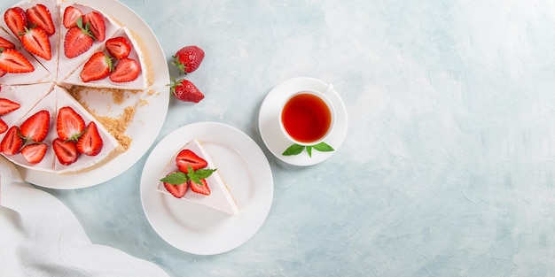 Chá doce de café da manhã e delicioso cheesecake com morangos frescos e receita caseira de menta sem assar em uma mesa de pedra azul copiar espaço