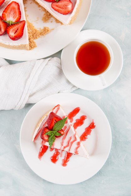 Chá doce de café da manhã e delicioso cheesecake com morangos frescos e receita caseira de menta sem assar em uma mesa de pedra azul Copiar espaço