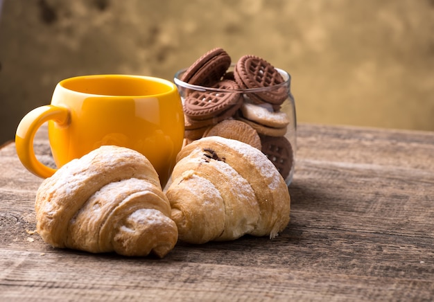 Chá e croissant na mesa de madeira