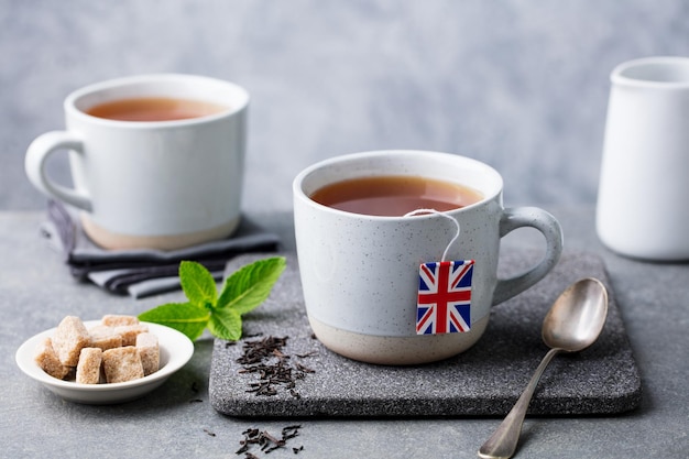 Foto chá em canecas com etiqueta de saquinho de chá de bandeira britânica fundo cinza close-up