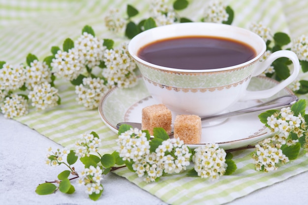 Chá em uma linda xícara branca. Café da manhã. Um ramo de spirea floração. Conceito japonês wabi sabi