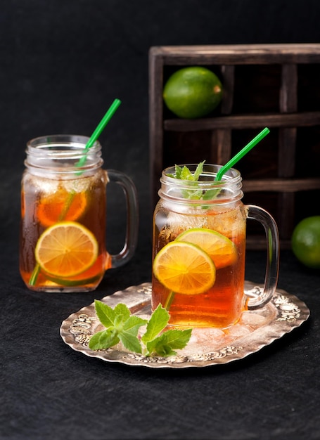 Chá frio com limão e hortelã em potes de vidro em fundo preto grunge