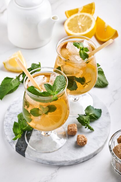 Chá gelado tradicional com limão e gelo em copos altos no fundo da mesa de mármore chá gelado com limão. foco seletivo. uma bebida refrescante de verão.