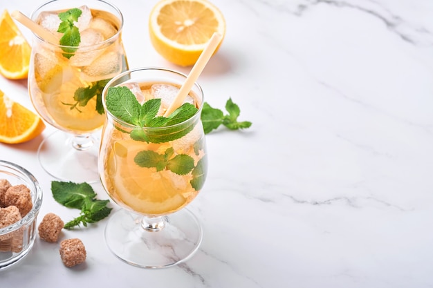 Chá gelado tradicional com limão e gelo em copos altos no fundo da mesa de mármore chá gelado com limão. foco seletivo. uma bebida refrescante de verão.