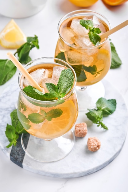 Chá gelado tradicional com limão e gelo em copos altos no fundo da mesa de mármore chá gelado com limão. foco seletivo. uma bebida refrescante de verão.