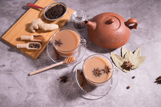 Chá indiano masala chá Chá com leite e especiarias em colheres de madeira em uma tábua de madeira