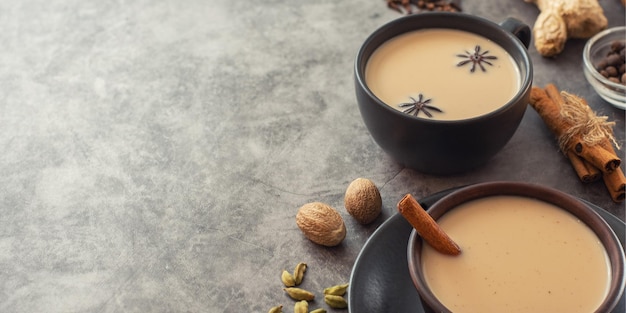 Chá Masala Chai indiano tradicional em xícara preta com especiarias em fundo cinza com espaço de cópia