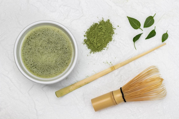 Chá matcha em uma tigela Matcha chá verde em pó batedor de bambu e colher medidora sobre a mesa