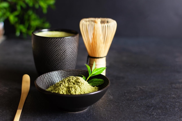 Chá matcha verde orgânico e acessórios de chá em cerimônia de chá japonesa de fundo preto