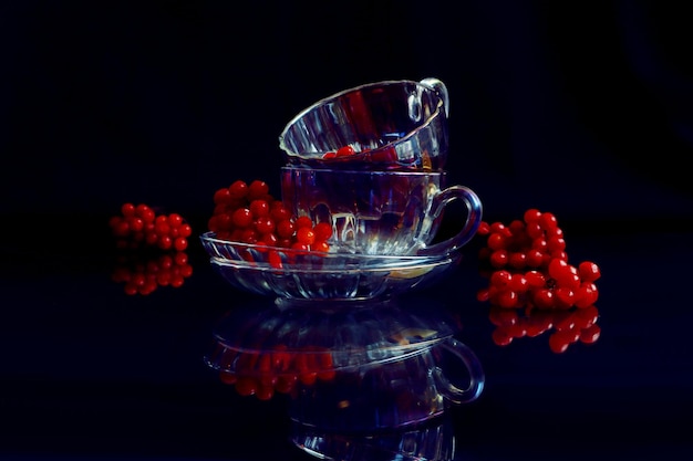 Chá medicinal com viburno duas canecas de vidro viburno neles em um fundo escuro ramos de viburno próximos à reflexão de objetos