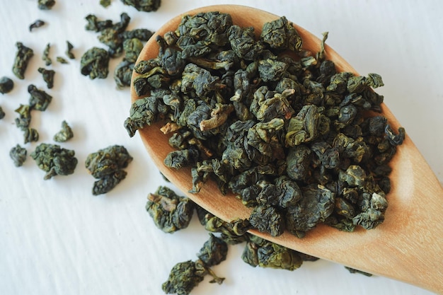 Chá oolong em uma colher de pau em um fundo branco é um chá chinês que traz benefícios à saúde