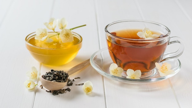 Chá preparado com flores de jasmim e mel em uma tabela.