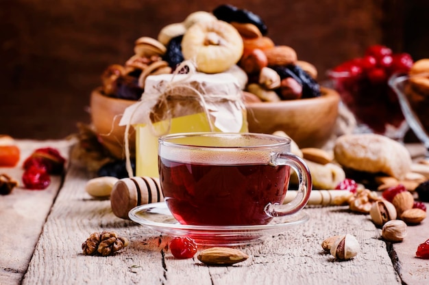 Chá preto do Oriente Médio em uma xícara com frutas secas e nozes Foco seletivo de fundo de madeira vintage