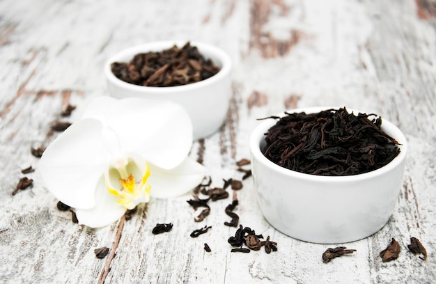 Chá preto e verde com flor de orquídea em um fundo de madeira