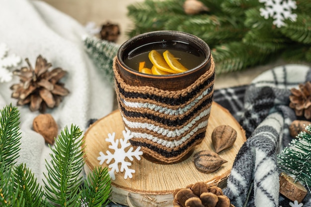 Chá preto quente e limão com decoração de inverno. Suéter aconchegante, galhos de árvores de abeto, nozes, flocos de neve. Arranjo sazonal festivo, conceito de bom humor, estilo rústico