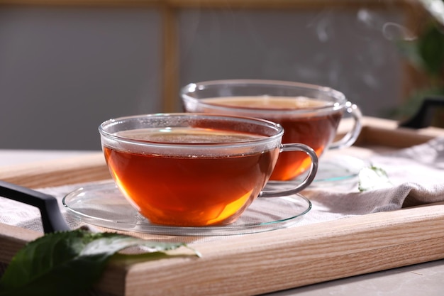 Chá quente aromático em copos de vidro na mesa cinza clara dentro de casa