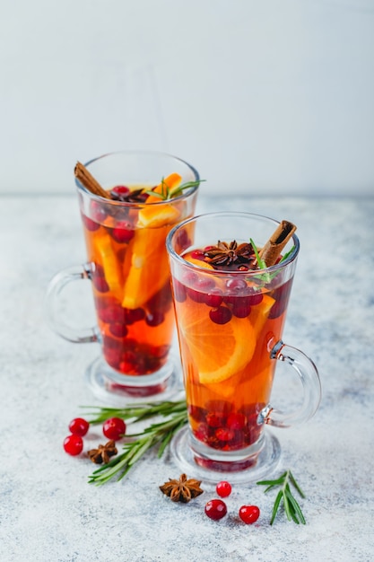 Chá quente com rodelas de laranja, cranberries e alecrim em copos altos. bebidas quentes de inverno e natal