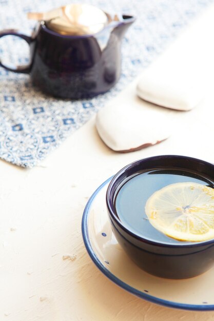 Chá quente com uma rodela de limão fresco em uma xícara de chá azul com corações de biscoitos e guardanapo azul