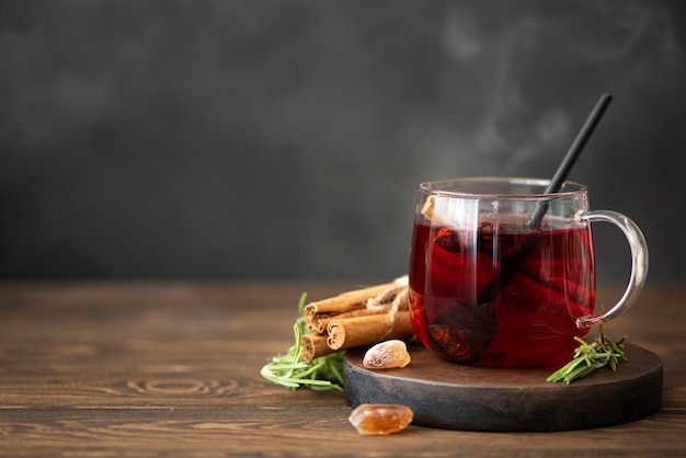Chá quente de hibisco com canela e açúcar em uma mesa de madeira