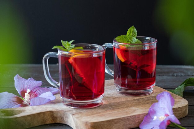 Foto chá quente de hibisco vermelho em uma caneca de vidro em uma mesa de madeira