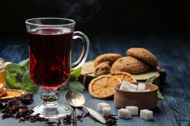 Chá quente de karkade vermelho com mel e biscoitos na mesa de madeira azul