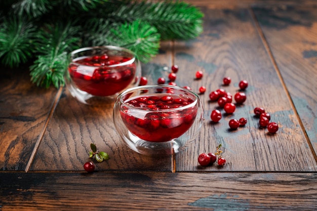 Chá quente de Natal ou inverno azedo de cranberry na madeira com galhos de pinheiro