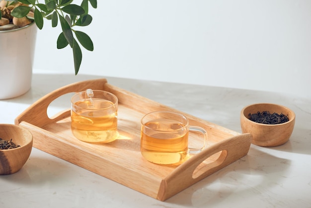 Chá quente é no copo colocado em uma bandeja de madeira