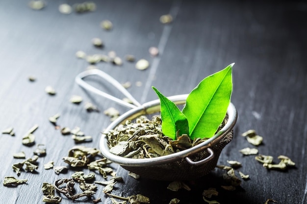 Chá verde aromático e folhoso em coador de metal antigo