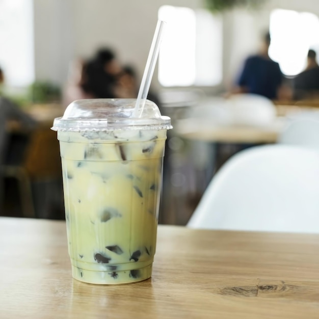 chá verde gelado com leite em copo de plástico colocado em mesa de madeira com um quarto todo branco