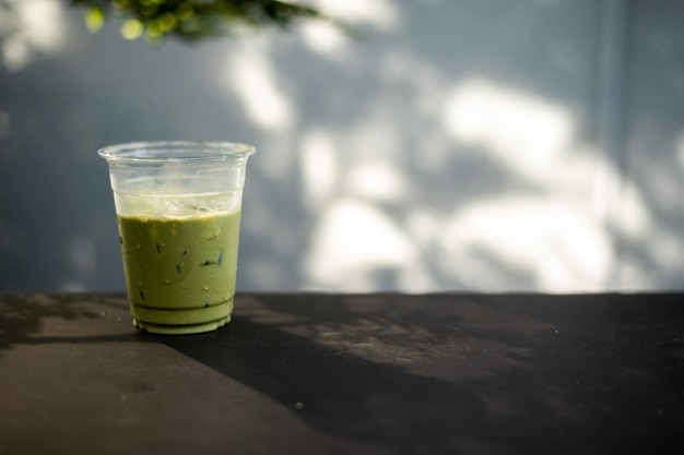 chá verde gelado com leite em copo plástico colocado na mesa preta