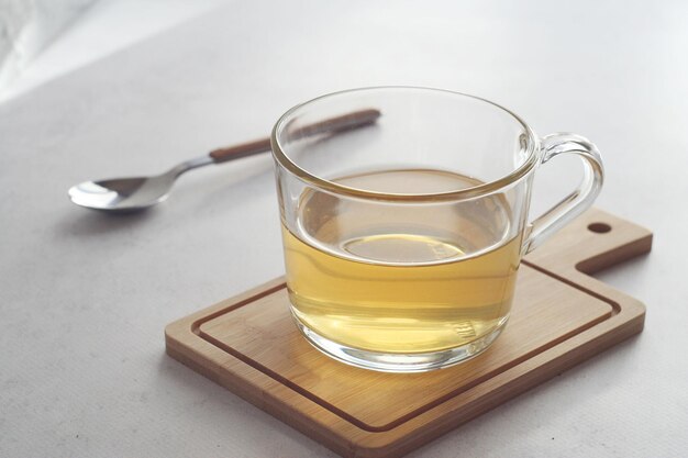 Chá verde Leite chinês oolong em uma caneca transparente sobre a mesa Atrás está uma colher de chá