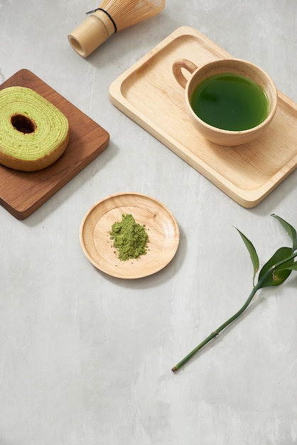 Chá verde matcha com leite em uma xícara e utensílios para cerimônia do chá com bolo alemão. Copie o espaço