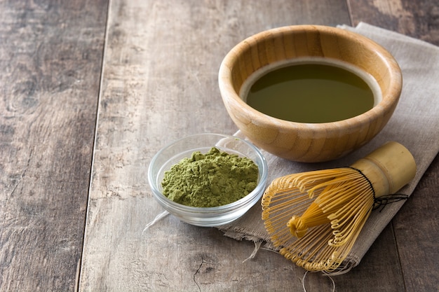 Chá verde Matcha em uma tigela e batedor de bambu na madeira