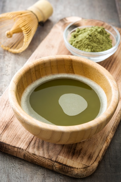 Chá verde Matcha em uma tigela e batedor de bambu na madeira