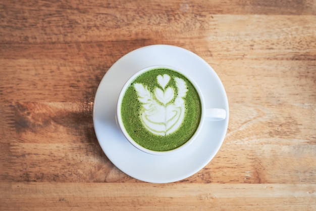 Chá verde matcha latte em um copo no fundo de madeira